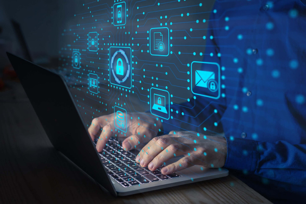 IT technician securing a laptop with cybersecurity protections displayed on screen